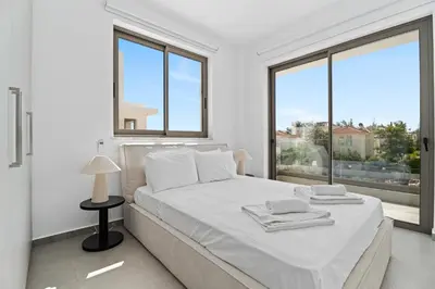 a white bedroom with a large bed and large windows at St Nicholas Luxury 3-Bed Villa in Paralimni
