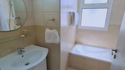 a bathroom with a sink and a tub and a window at STAY Sunny Bay Villa in Protaras