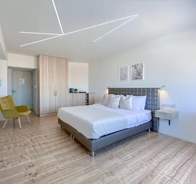 a bedroom with a large bed and a chair at Plateia Suite Brillante in Nicosia