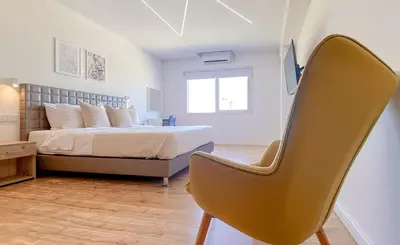 a bedroom with a bed and a chair in it at Plateia Suite Brillante in Nicosia