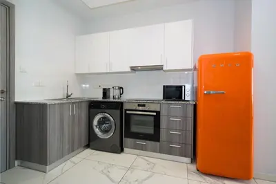 a kitchen with an orange refrigerator and a washing machine at Luxury Modern Larnaca Central in Larnaka