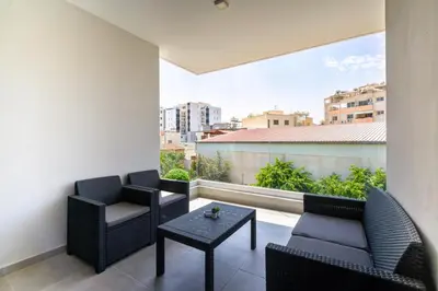 a balcony with chairs and a table and a large window at Luxury Modern Larnaca Central in Larnaka