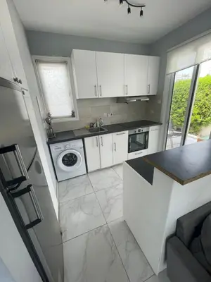 a kitchen with white cabinets and a washer and dryer at Azure Waves House in Voroklini