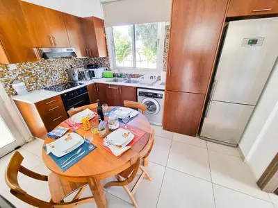 a small kitchen with a wooden table with chairs at Poser Beach Villa With Private Pool And BBQ in Pervolia