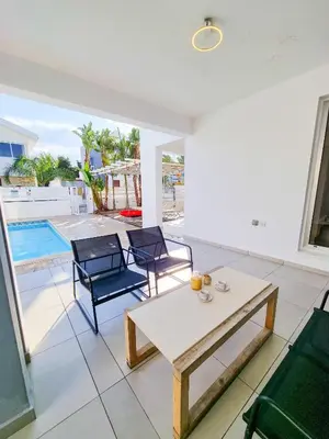 a living room with a table and chairs and a pool at Poser Beach Villa With Private Pool And BBQ in Pervolia