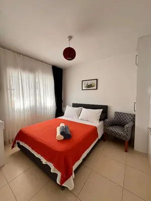 a bedroom with a bed with a red blanket and a chair at Flat in Kyrenia, Cyprus in Kérynia