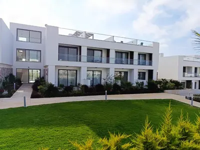 a white house with a green lawn in front of it at Deja Blue Apartments, North Cyprus