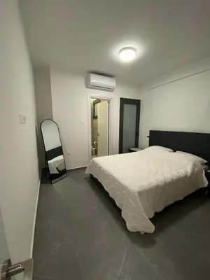 a bedroom with a white bed and a chair at Mall View Modern PentHouse in Larnaka