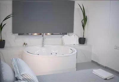 a white bathroom with a tub and a window at Plateia Suite Deluxe in Nicosia