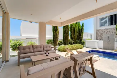 a patio with a couch and a table and chairs at Levanda Hills Haven in Protaras in Paralimni