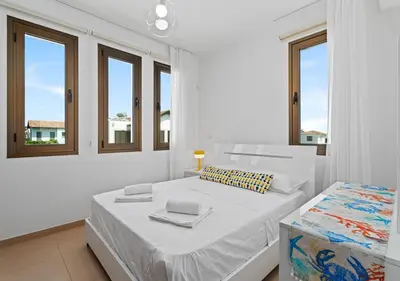 a white bedroom with a bed and two windows at Levanda Dreams 8 in Paralimni