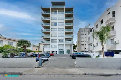 a parking lot with cars parked in front of a building at The lighthouse 1 bedroom 604 in Larnaka