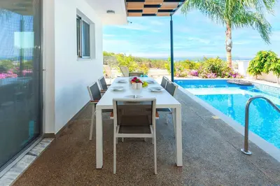 a white table and chairs next to a swimming pool at Royal Panoramic View 3Bdr Villa with pool Ayia Napa in Ayia Napa