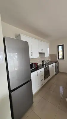 a kitchen with white cabinets and a stainless steel refrigerator at Spacious 1BDR Sea View & Pool in Voroklini