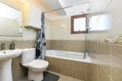 a bathroom with a toilet and a tub and a sink at Nissi Apartment #102 in Ayia Napa