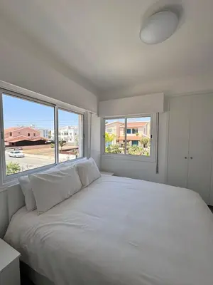 a bedroom with a large white bed with two windows at Dhekelia Beach house - Pyla, Larnaca in Pyla