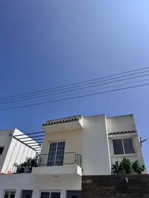 a white house with a balcony and a blue sky at Dhekelia Beach house - Pyla, Larnaca in Pyla