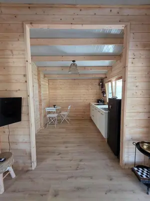 a room with wooden walls and a kitchen with a refrigerator at Kellaki Relaxation Cottage in Kellaki