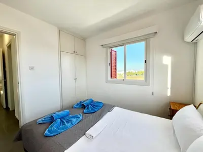 a bedroom with a bed with blue pillows on it at STAY Capari Light Apartment in Protaras