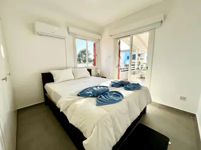 a bedroom with a large bed with blue pillows on it at STAY Capari Light Apartment in Protaras