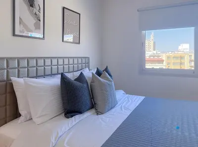 a bed with blue and white pillows and a window at Plateia suite Grigio in Nicosia