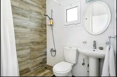 a bathroom with a toilet and a sink and a mirror at Amazing Sea View -3 Bed Ground Floor Garden Apartment in Kérynia