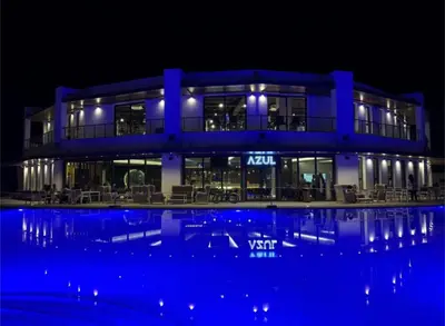 a blue building with a swimming pool at night at Caesar Blue Studio Sea View Apartment in Boğaz