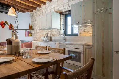 a kitchen with a wooden table with chairs and a dining room at Exquisite 2BR modern village house w private pool in Ayios Tykhonas