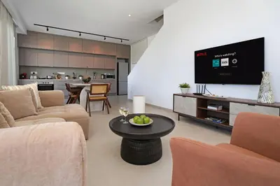 a living room with a couch and a tv and a table at Princess Anne Luxury Villa - Large Pool in Protaras