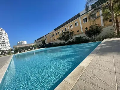 a large blue swimming pool in a building at Family friendly modern flat in Caesar Resort &SPA, Long Beach İSKELE, KKTC in Iskele