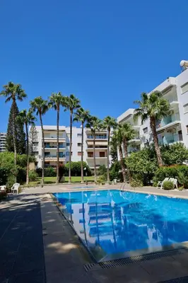 a swimming pool with palm trees and condos at Beach Front Apartment in Limassol
