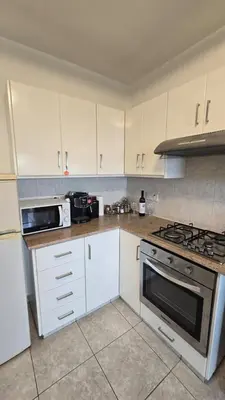 a kitchen with white cabinets and a stove top oven at ERIKA Sea Breeze Makenzie in Larnaka