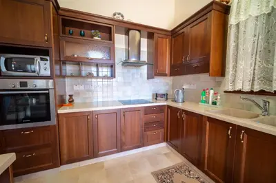 a kitchen with wooden cabinets and a sink at Casa Harmonia Traditional Stone House, Escape to Silence Soul and Serenity in Nature with 2 Bedrooms, Fireplace and Mountain Breeze in Mandria