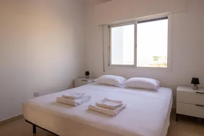a white bedroom with a bed with towels on it at Sea View Stay 200m to Beach in Voroklini