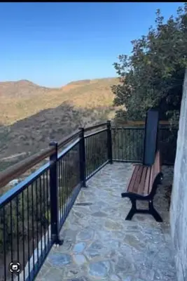 a wooden bench sitting on a balcony with a fence at The Heart of Moutoullas in Moutoullas