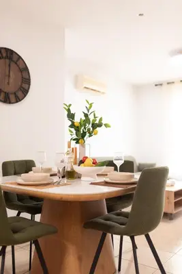 a dining room table with chairs and a clock on the wall at TelMar Sunrise View 100m from the Sea in Larnaka