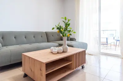 a living room with a couch and a table with a vase at TelMar Sunrise View 100m from the Sea in Larnaka