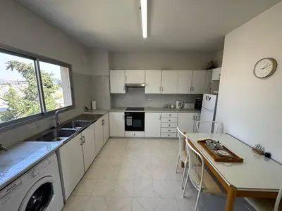 a kitchen with white cabinets and a table and a sink at Sfina Sea view apartment by Ezoria villas in Limassol