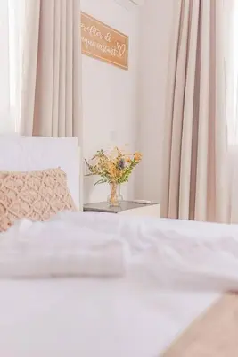 a vase of flowers on a table next to a bed at TelMar Royal Villa Sea View in Mazotos
