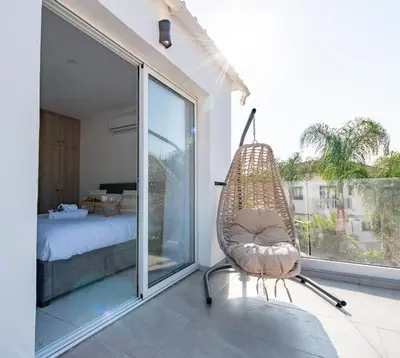 a rattan chair in a room with a bedroom at TelMar Sea View - 2 min walk to the Beach in Voroklini