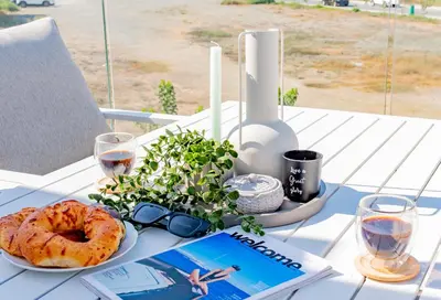 a table with a book and a plate of bagel and glasses at TelMar Sea View - 2 min walk to the Beach in Voroklini