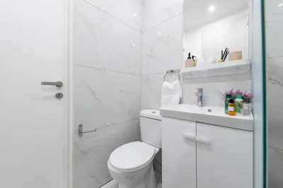 a white bathroom with a toilet and a sink at TelMar Sea View - 2 min walk to the Beach in Voroklini