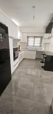a kitchen with white cabinets and a large floor at Modern apartment in North Nicosia