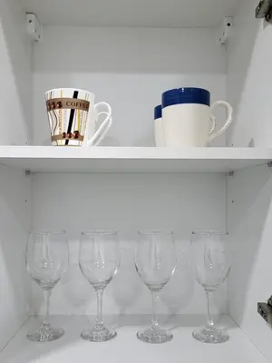 a white shelf with wine glasses on it at Chryso Apts Protaras in Paralimni