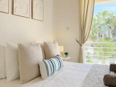 a white bed with pillows and a window at 5-Min Walk to Beach - Bright 2-BR Home with Private Garden & Sunset Views in Voroklini