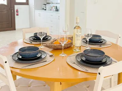 a dining room table with a bottle of wine and glasses at 5-Min Walk to Beach - Bright 2-BR Home with Private Garden & Sunset Views in Voroklini