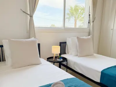 two beds in a room with a window at 5-Min Walk to Beach - Bright 2-BR Home with Private Garden & Sunset Views in Voroklini
