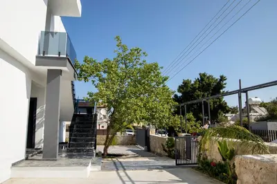 a white house with stairs and a tree on the sidewalk at Apartment Northern Cyprus