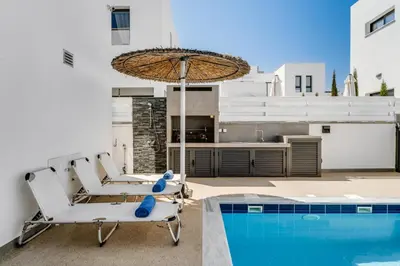 a patio with two chairs and an umbrella next to a swimming pool at Villa Alassia 16 by Ezoria Villas in Paralimni