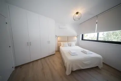a white bedroom with a bed and a window at CasaMar - Upscale One-Bedroom Apartment by the Sea in Larnaka